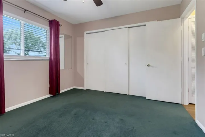 Unfurnished bedroom featuring ceiling fan and dark colored carpet