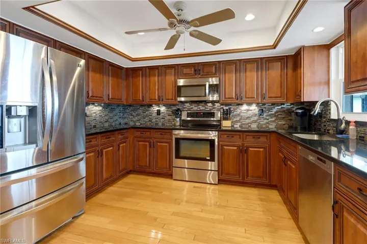 Kitchen featuring ceiling fan, sink, dark stone countertops, and appliances with stainless steel finishes