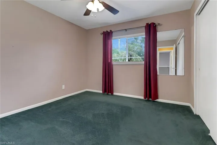 Unfurnished room featuring dark colored carpet and ceiling fan