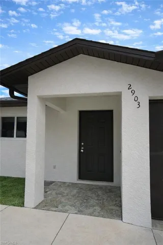 Doorway to property featuring stucco siding