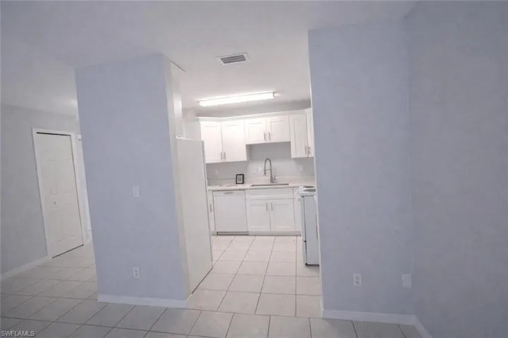 Kitchen featuring light countertops, white cabinets, white appliances, and light tile patterned flooring