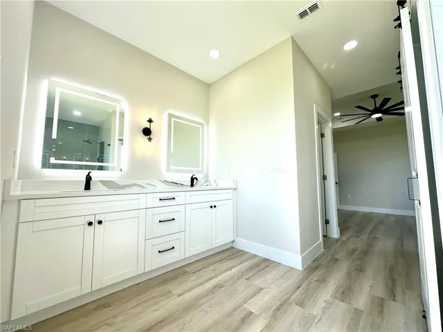 Contemporary bathroom vanity featuring dual sinks, illuminated mirrors, and black fixtures