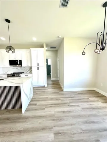 Contemporary kitchen featuring white cabinetry, a waterfall-edge island with vertical paneling, and wood-finish flooring