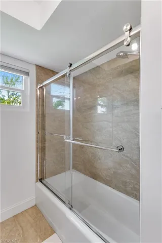 Bathroom with enclosed tub / shower combo and tile patterned flooring