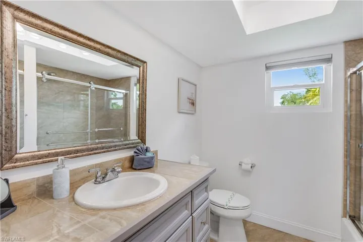 Bathroom featuring tile patterned floors, toilet, a shower with door, and vanity