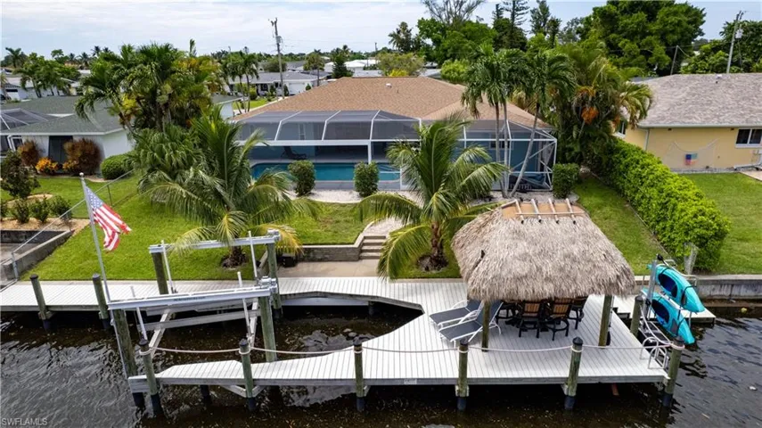 View of dock with glass enclosure, a water view, and a yard