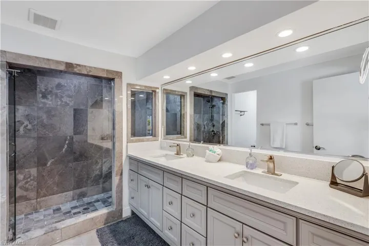 Bathroom with a shower with door, tile patterned flooring, and vanity
