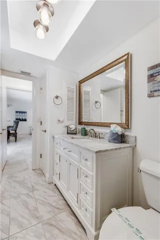 Bathroom with a raised ceiling, tile patterned flooring, toilet, and vanity