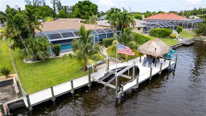 Dock area featuring glass enclosure, a water view, and a yard