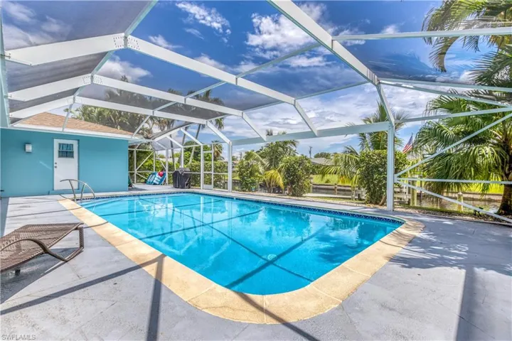 View of pool featuring glass enclosure and a patio