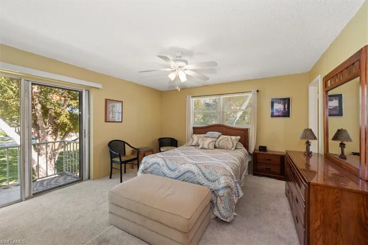 Bedroom with access to balcony, light colored carpet, a ceiling fan