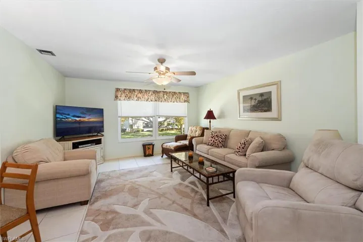 Living room with tile patterned floors and ceiling fan