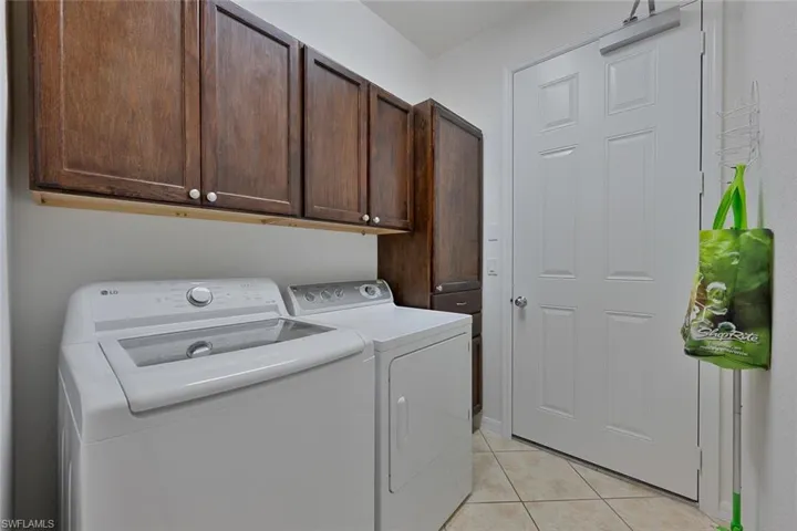Washroom featuring cabinet space, light tile patterned floors, and independent washer and dryer
