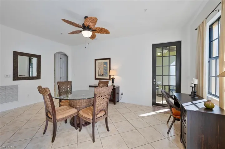 Dining space featuring arched walkways, a ceiling fan, and light tile patterned flooring