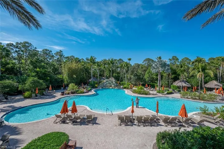 Community pool with a patio area and view of scattered trees