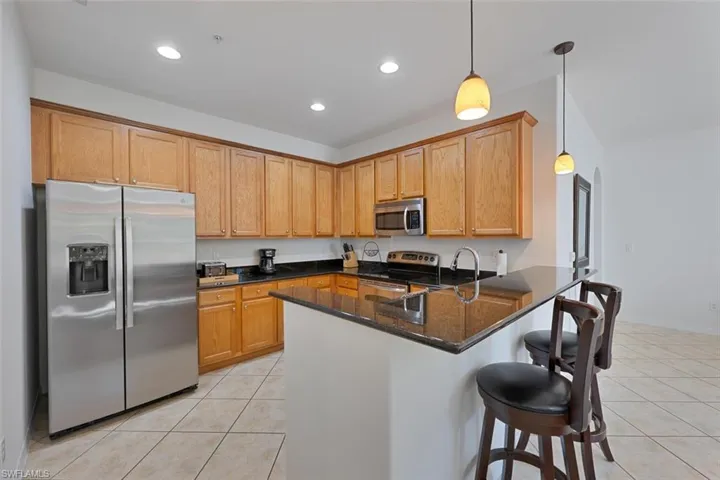 Kitchen featuring appliances with stainless steel finishes, light tile patterned floors, pendant lighting, a peninsula, and recessed lighting
