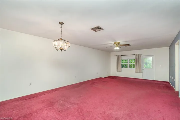 Spare room with carpet flooring and ceiling fan with notable chandelier