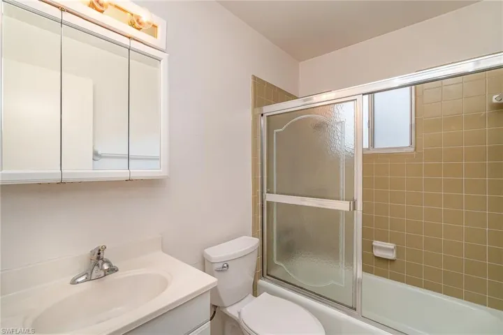Full bathroom featuring oversized vanity, bath / shower combo with glass door, and toilet