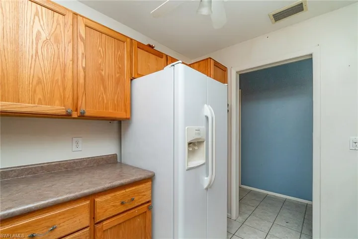 Kitchen with ceiling fan, light tile flooring, and white refrigerator with ice dispenser
