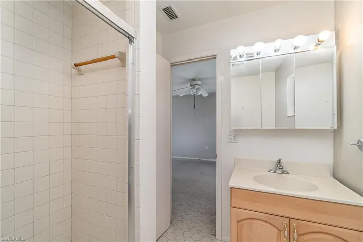 Bathroom with a shower with door, tile floors, vanity, and ceiling fan