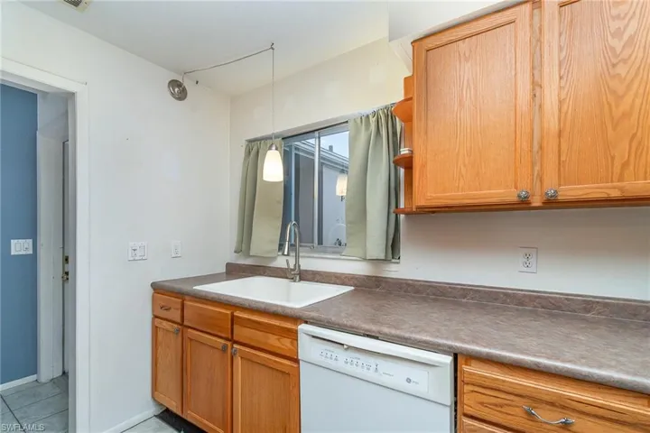 Kitchen featuring light tile floors, sink, white dishwasher, and pendant lighting