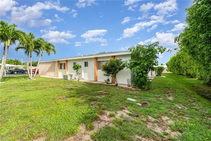 Back of house with a yard and central AC unit