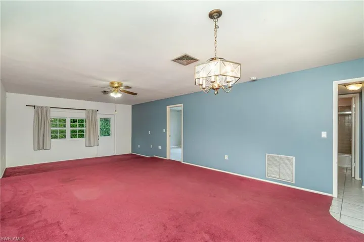 Spare room featuring carpet and ceiling fan with notable chandelier