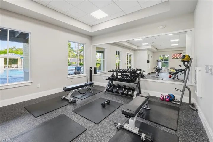 Fitness center featuring a large wall mirror, recessed lighting, and rubberized flooring