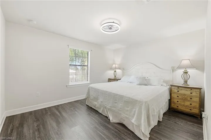 Bright interior featuring light-toned walls, wood-finish flooring, a ceiling-mounted light fixture, and a window with horizontal blinds