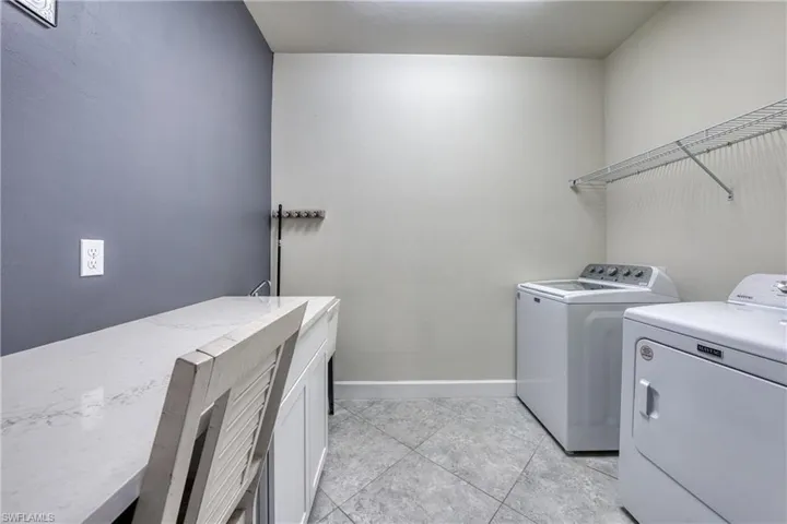 Utility room featuring a built-in countertop, undermount sink with faucet, tiled flooring, and wall-mounted shelving