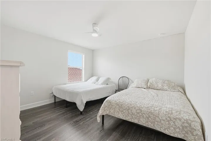 Bright room featuring wood-finish flooring, a white ceiling fan with integrated lighting, and a window with blinds