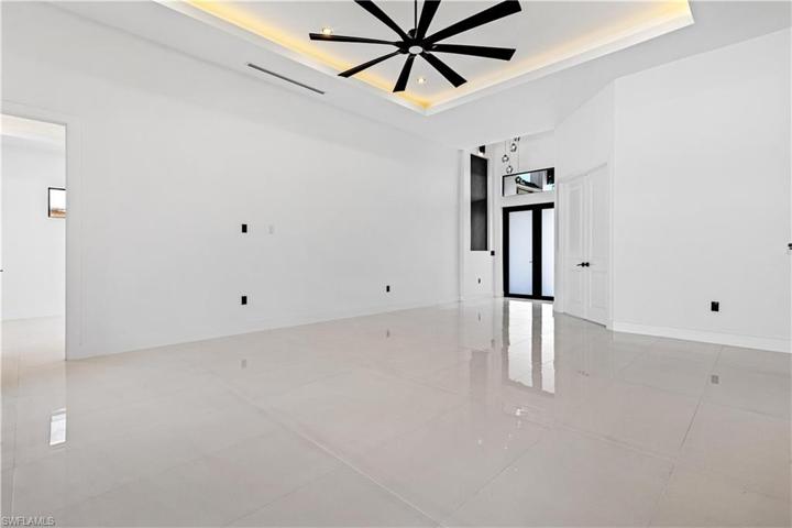 Living Room - 14 ft Cove Ceiling with Smooth Wall Paint, Wood Baseboards (throughout the home) & Designer's Fan