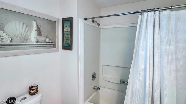 White fiberglass shower enclosure with a chrome shower head and faucet set
