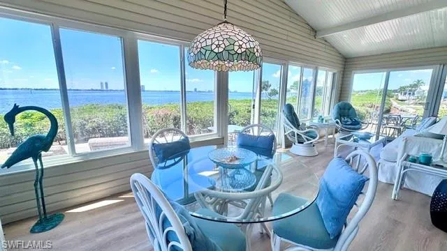 Sunroom featuring extensive fenestration, water scenery, and wood-finish flooring