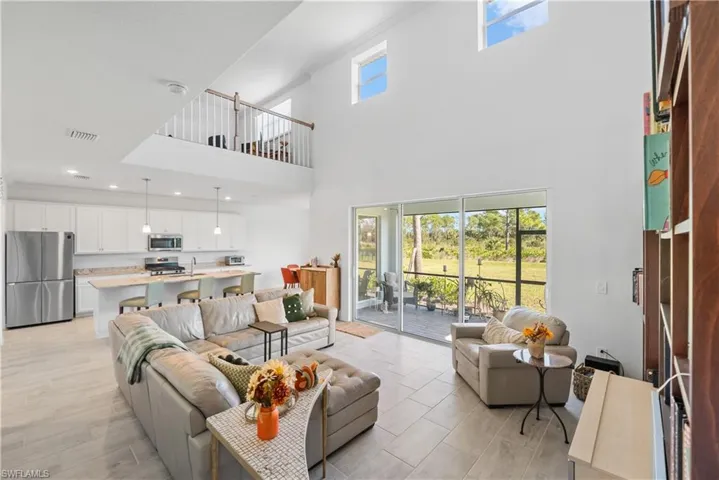 Living room featuring light wood-type flooring and a towering ceiling