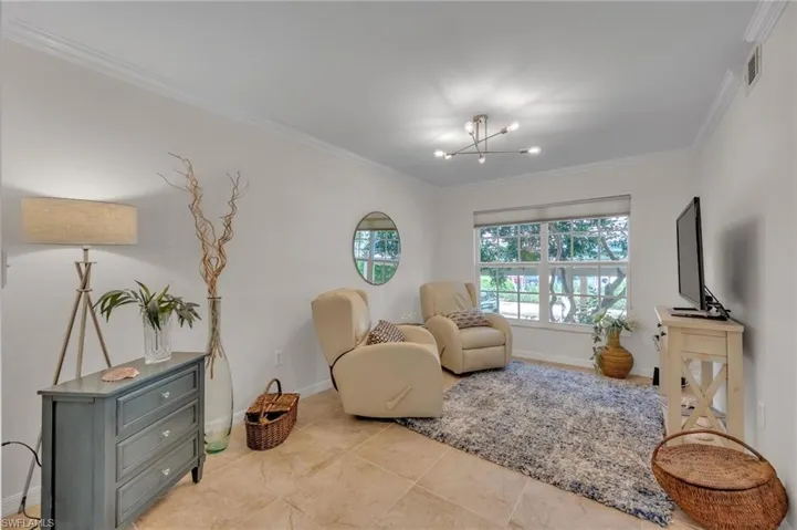 Bright interior space featuring large windows, crown molding, a modern multi-light ceiling fixture, and neutral tile flooring
