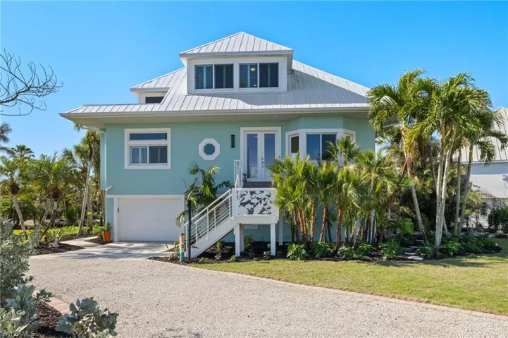 Coastal home featuring a garage and a front lawn