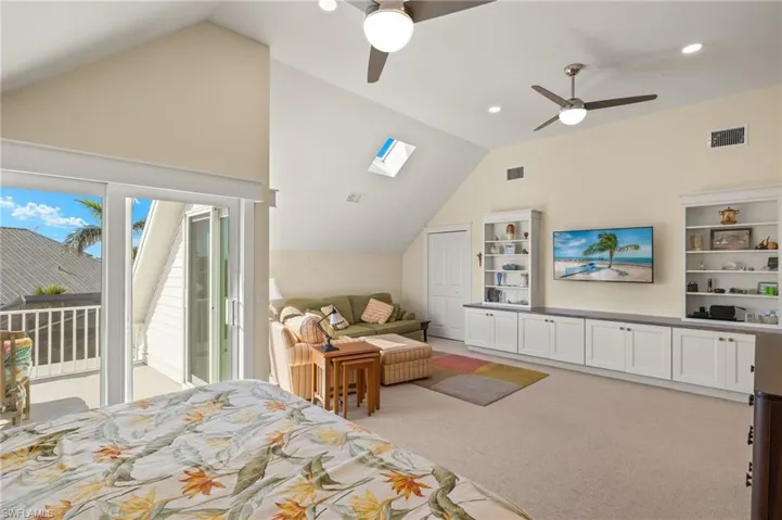 Carpeted bedroom featuring lofted ceiling with skylight, access to exterior, and ceiling fan