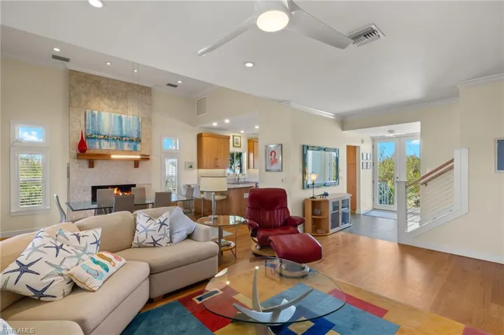 Living room featuring a fireplace, light hardwood / wood-style flooring, ceiling fan, crown molding, and french doors
