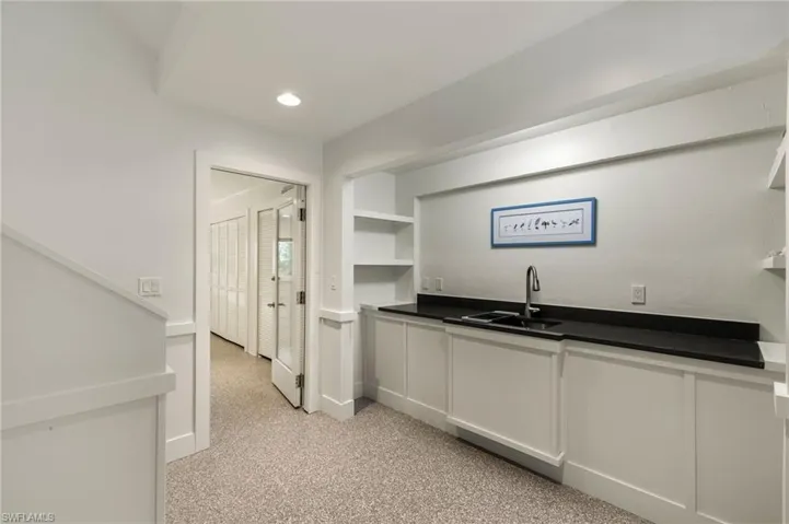 Kitchen featuring built in shelves, sink, and white cabinets