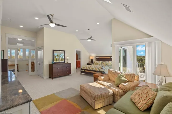 Carpeted bedroom featuring high vaulted ceiling, multiple windows, and access to outside