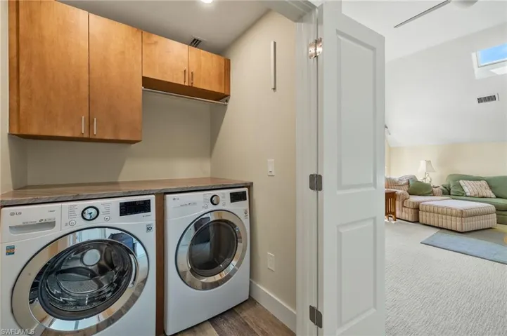 Washroom with cabinets, washer and clothes dryer, and dark carpet