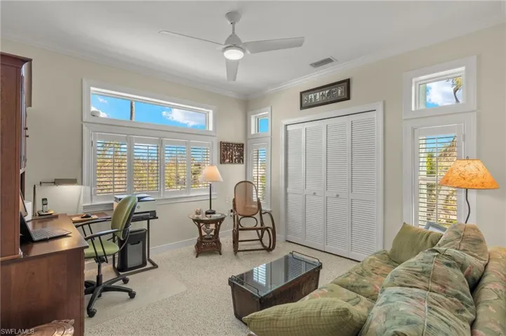 Office area with ornamental molding, plenty of natural light, light colored carpet, and ceiling fan