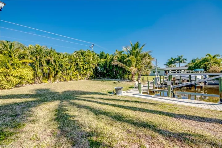View of green lawn featuring boat lift and a dock