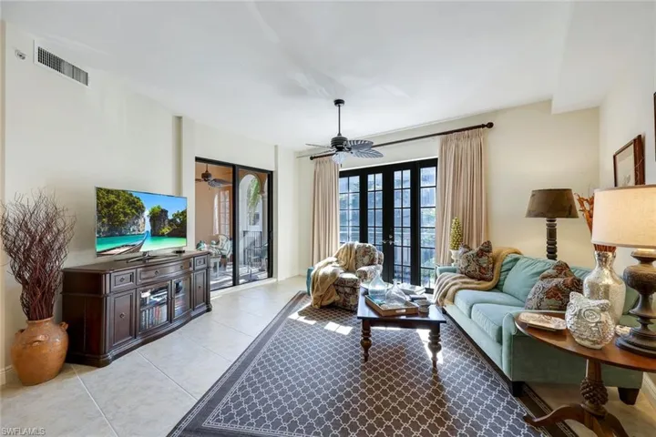Living room with light tile patterned floors, french doors, and ceiling fan