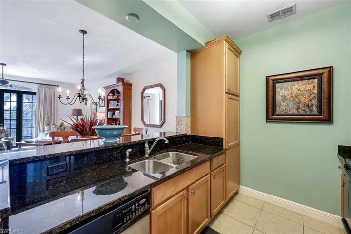 Kitchen with sink, dark stone countertops, a chandelier, pendant lighting, and light tile patterned floors