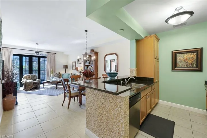 Kitchen with kitchen peninsula, dishwasher, light tile patterned floors, and sink