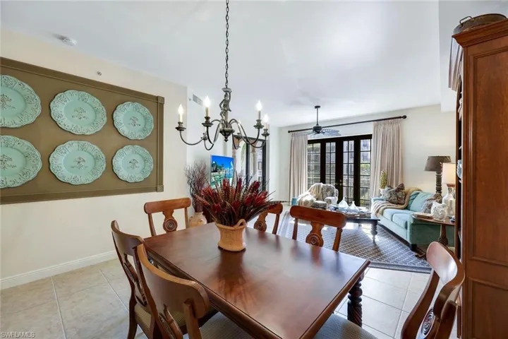 Tiled dining room featuring french doors and ceiling fan with notable chandelier