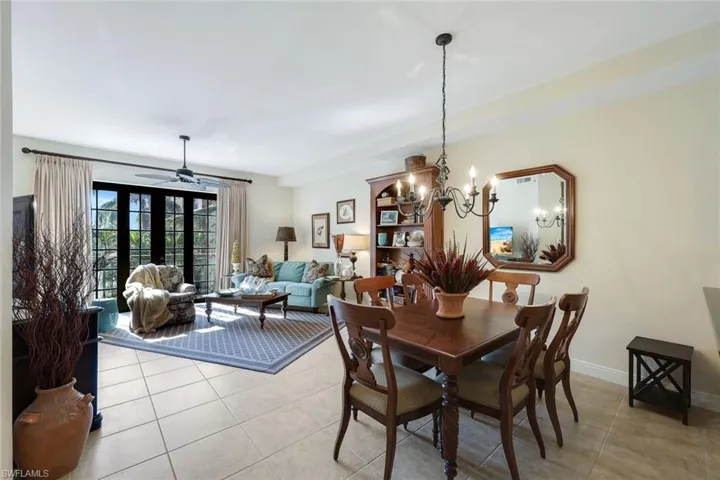 Tiled dining space featuring french doors and ceiling fan with notable chandelier