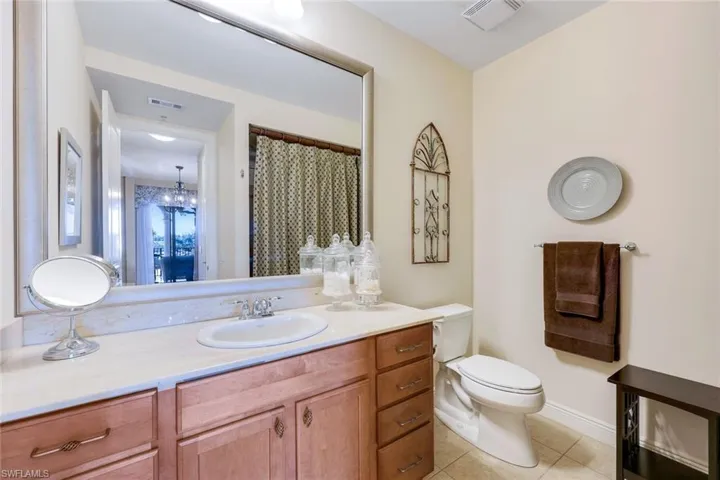 Bathroom with tile patterned flooring, vanity, a chandelier, and toilet